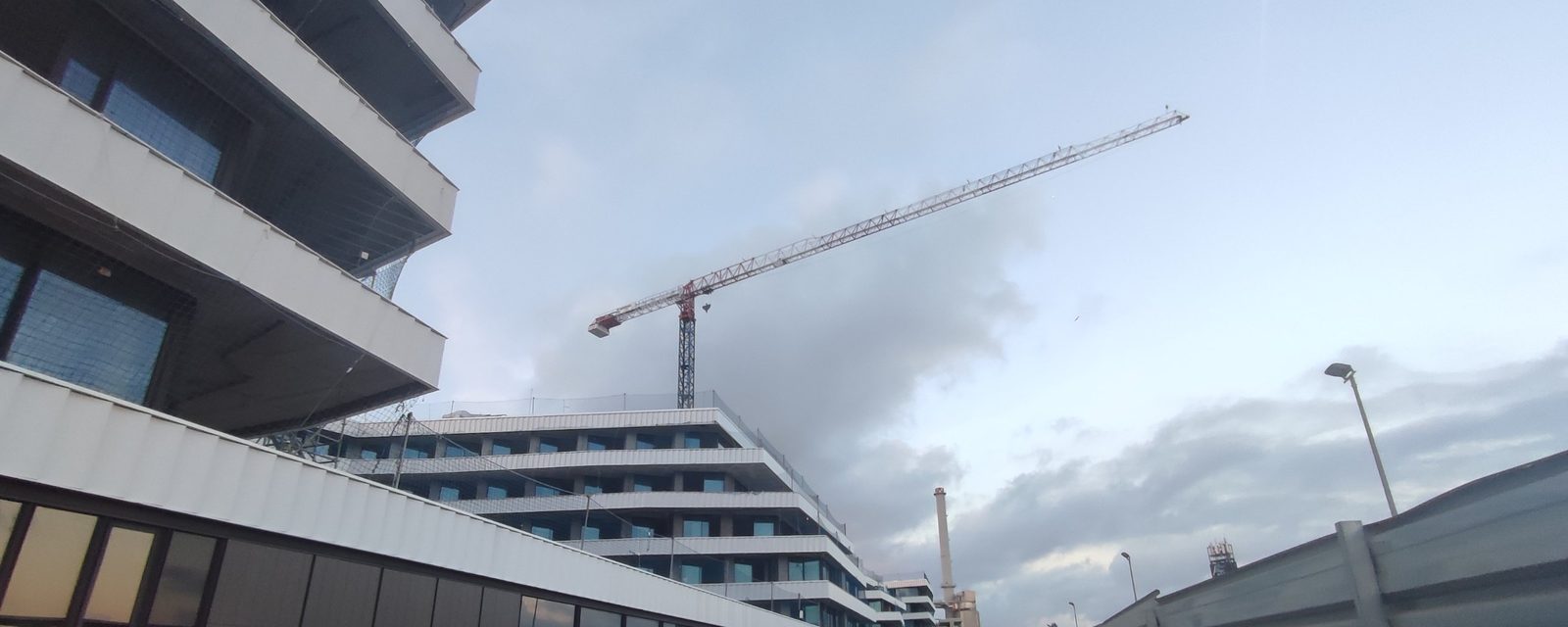 Edificio del hotel en obra, con la grúa torre y la chimenea de la central de climatización